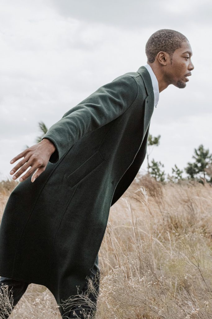 pexels-photo-15538488-15538488 Portrait of a man in a green coat posing in a rural landscape, showcasing modern fashion style.